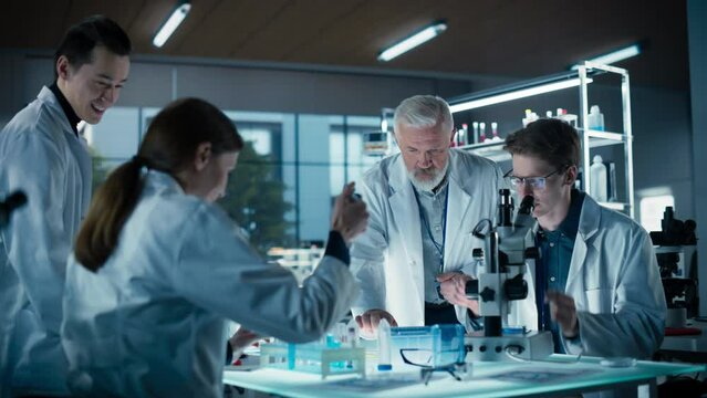 Modern Medicine Research Laboratory: Diverse Team of Smart Young Scientists Conducting an Experiment Under Senior Professor's Supervision. Advanced Microbiology Lab with High Tech Equipment