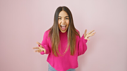 Excited young hispanic woman in a pink sweater over a pink wall expressing happiness