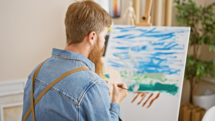 Handsome young redhead man, an ambitious artist, immerse in drawing at the interior art studio,...