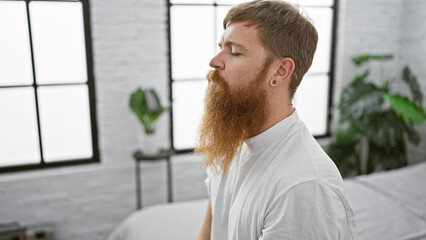 Serene morning, young redhead man comfortably nestled in cozy bed, breathing in calm air. quietly awake, sitting in bedroom, serious concentration on balancing the rhythm of breath.