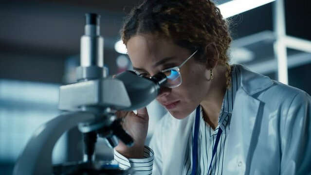 Close Up Portrait of a Multiethnic Student Working on a Research Project in College. Medical Research Scientist Looking at Biological Samples Under a Microscope in an Applied Science Laboratory