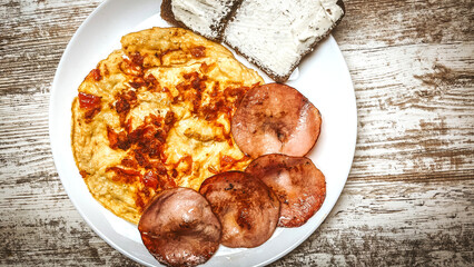 Fried eggs on a stylish ceramic plate with handles with fried bacon, cherry tomatoes, tomato paste and bread toast on a dark background. Breakfast, lunch and dinner. Delicious food.