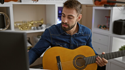 Captivating young hispanic man engrossed in playing a classic guitar melody at a music studio...