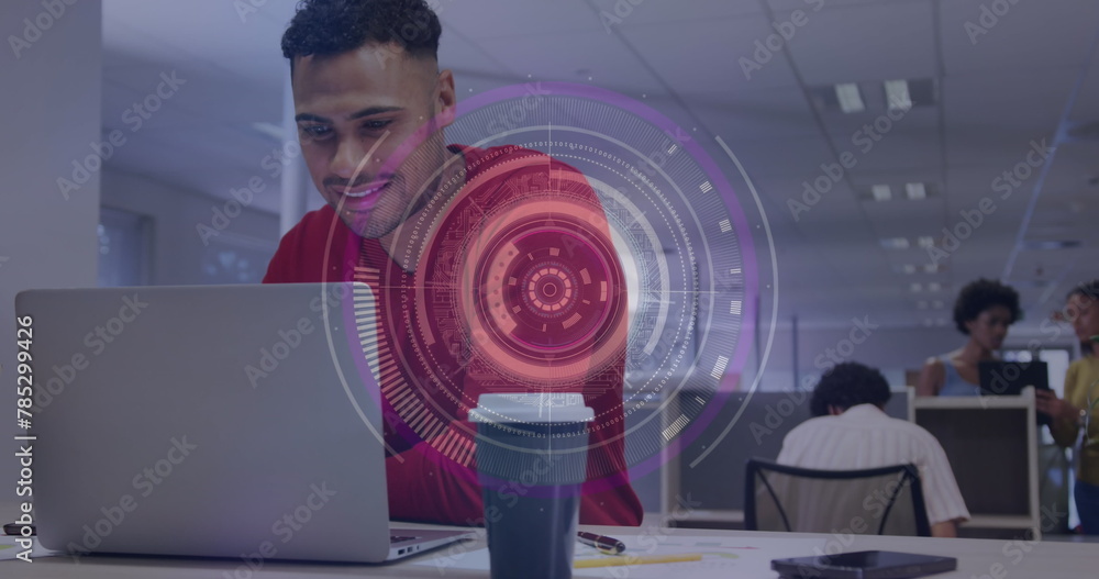 Poster image of round scanner against biracial man smiling while using a laptop at office