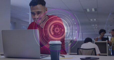 Image of round scanner against biracial man smiling while using a laptop at office