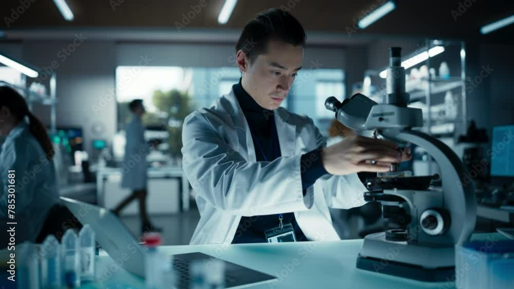 Poster Cinematic Portrait of a Young Graduate Student Working in a Laboratory, Using Advanced Microscope, Writing Down Research Data on a Computer. Multiethnic Biotechnology Specialist Using Modern Tools