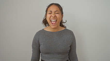 Young hispanic woman screaming against an isolated white background, expressing intense emotion.