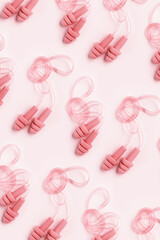 Creative pattern made powder pink silicone earplugs for swim, sleep, rest on pink background....