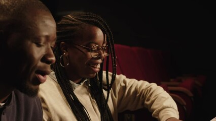 Medium shot of two young Black theatre actors sitting together with scenario on sheets of paper and revising scene during rehearsal or audition
