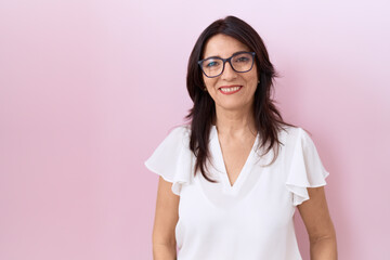 Middle age hispanic woman wearing casual white t shirt and glasses relaxed with serious expression...