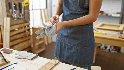 African american woman wearing safety gloves in a woodworking studio