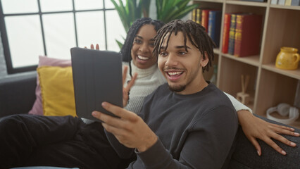 Happy couple engaging in a video call at home using a tablet, showcasing technology and relationships indoors.