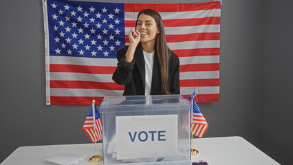 Young hispanic woman smiling in a voting room with american flags, representing democratic...