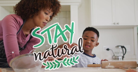 Image of stay natural text over happy african american mother and son cooking at home