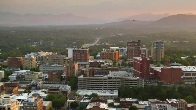 USA travel destination landscape. Panoramic view of North Carolina Appalachian city Asheville with downtown architecture and Blue Ridge Mountain hills in distance at sunset