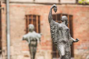 Skulptur Frau isst Weintrauben vor Backsteinhaus © lebaer