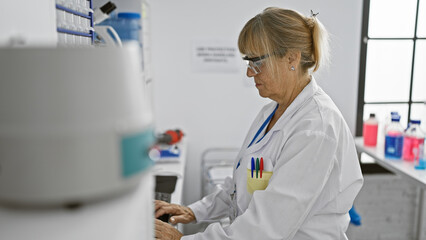 In lab bliss, middle age blonde scientist woman immersed in research, working at computer in...