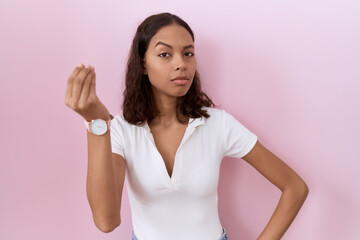 Young hispanic woman wearing casual white t shirt doing italian gesture with hand and fingers...
