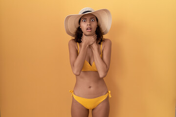 Young hispanic woman wearing bikini and summer hat shouting suffocate because painful strangle. health problem. asphyxiate and suicide concept.