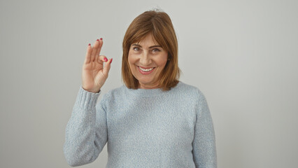 Smiling mature woman giving ok gesture isolated on white background