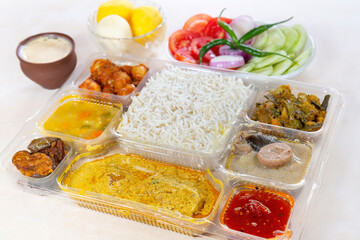 Indian Bengali Mixed Thali meal with vegetarian and non-vegetarian dishes, comprising plain rice, vegetable dishes along with spicy fish curry.