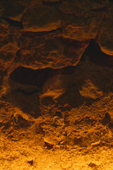 Mysterious image of a cave with amber lighting highlighting intricate details and shadows inviting...