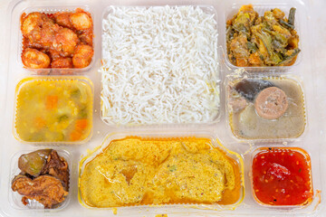 Indian Bengali Mixed Thali meal with vegetarian and non-vegetarian dishes, comprising plain rice, vegetable dishes along with spicy fish curry.