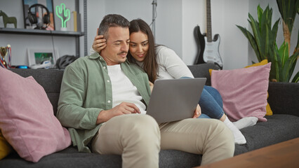 A loving couple enjoying time together with a laptop in a cozy living room.