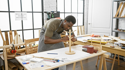 African american man carefully assembles wooden model in bright, organized carpentry workshop.
