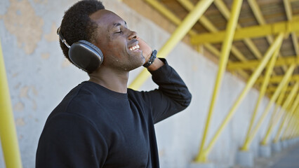 A happy african american man enjoys music with headphones in an urban outdoor setting with yellow...