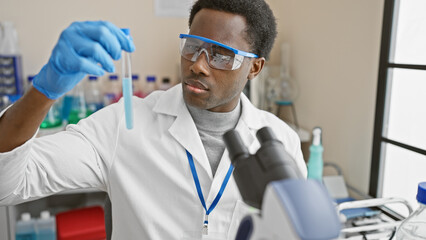 African american scientist analyzing a test tube in a laboratory setting, exemplifying healthcare...