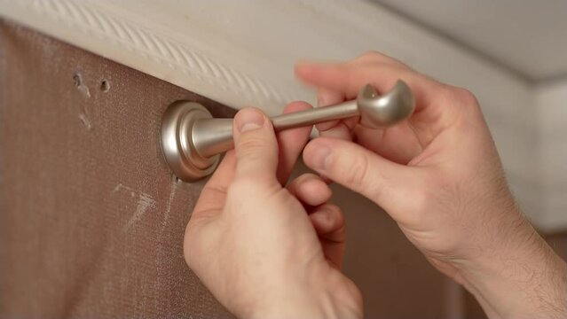 Close up man install mechanism for in wall to hang cornice in old apartment. Concept cheap home renovation in old room. Brass curtain hardware and accessories for curtain rod