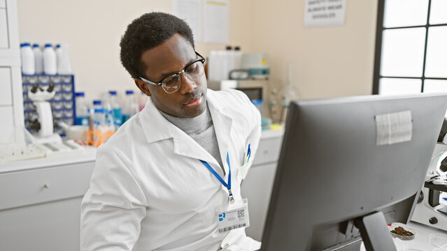 African american man analyzing data on computer in laboratory setting, exuding professionalism and focus.