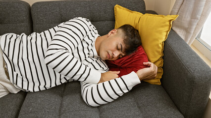 Attractive, young hispanic man found comfortable relaxation, sleeping soundly on the cozy sofa,...