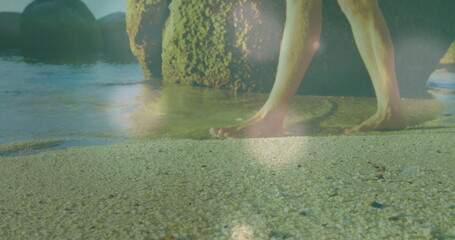 Naklejka premium Image of glowing spots over caucasian woman walking at beach