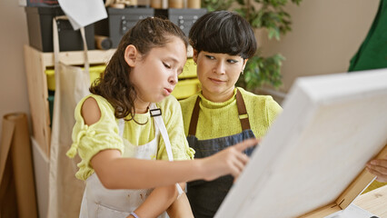 Teacher, student artist duo in apron, paintbrush in hand, bonding over a drawing lesson, sitting,...