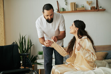cheerful loving man in homewear helping his disabled wife to change into pajama in bedroom at home