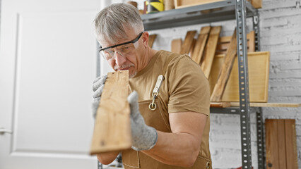 A mature man examines a wooden plank in a well-organized carpentry workshop, conveying skill and...
