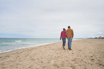 Couple walking in beach sand by the ocean