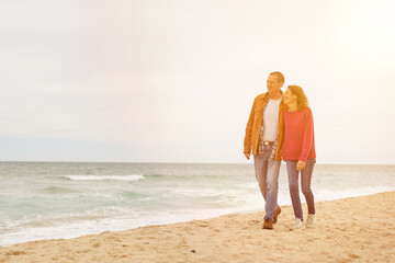 Mature Couple walking in beach sand by the ocean at sunset