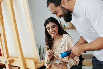 loving jolly husband helping his inclusive good looking wife to paint on easel while at home - obrazy, fototapety, plakaty