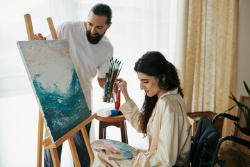 loving cheerful couple of bearded man and disabled woman painting on easel together at home - obrazy, fototapety, plakaty