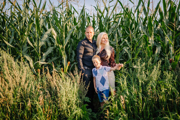 Valmiera, Latvia - August 17, 2024 - A family of three stands in a cornfield, with tall green stalks surrounding them, in casual attire enjoying the outdoors.