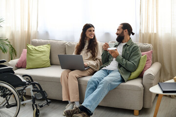 joyful bearded man spending quality time at laptop with his disabled beautiful wife, drinking coffee