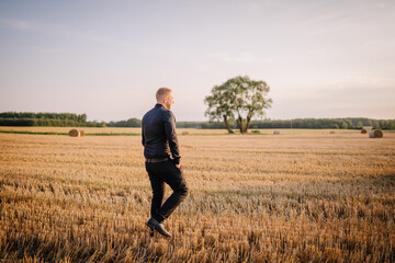 Valmiera, Latvia - August 17, 2024 - A man in business attire walks across a harvested field with...