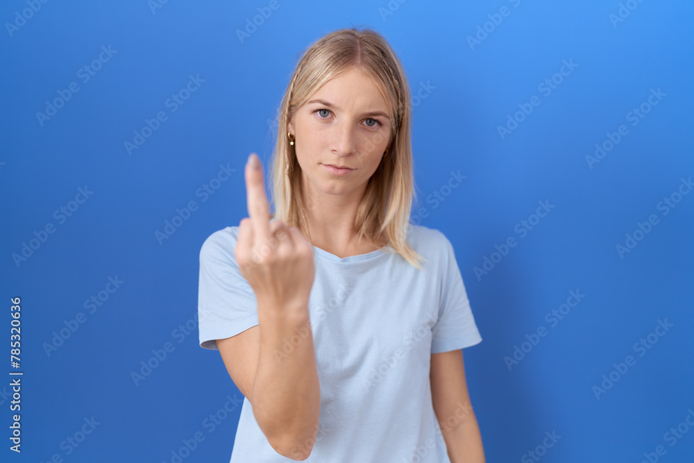 Sticker Young caucasian woman wearing casual blue t shirt showing middle finger, impolite and rude fuck off expression