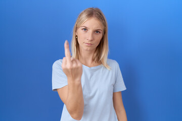 Young caucasian woman wearing casual blue t shirt showing middle finger, impolite and rude fuck off expression