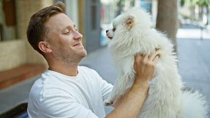 Cheerful young caucasian man confidently smiling while sitting with his joyful puppy on a city...