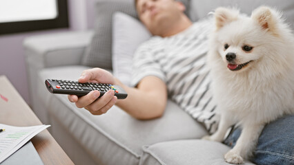 Handsome young caucasian man and his loyal dog relaxing, deeply engrossed in a captivating film on...