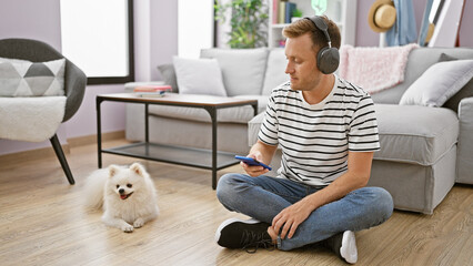 Engrossed young caucasian man sitting on the floor at home, deeply focused on a song playing on his...